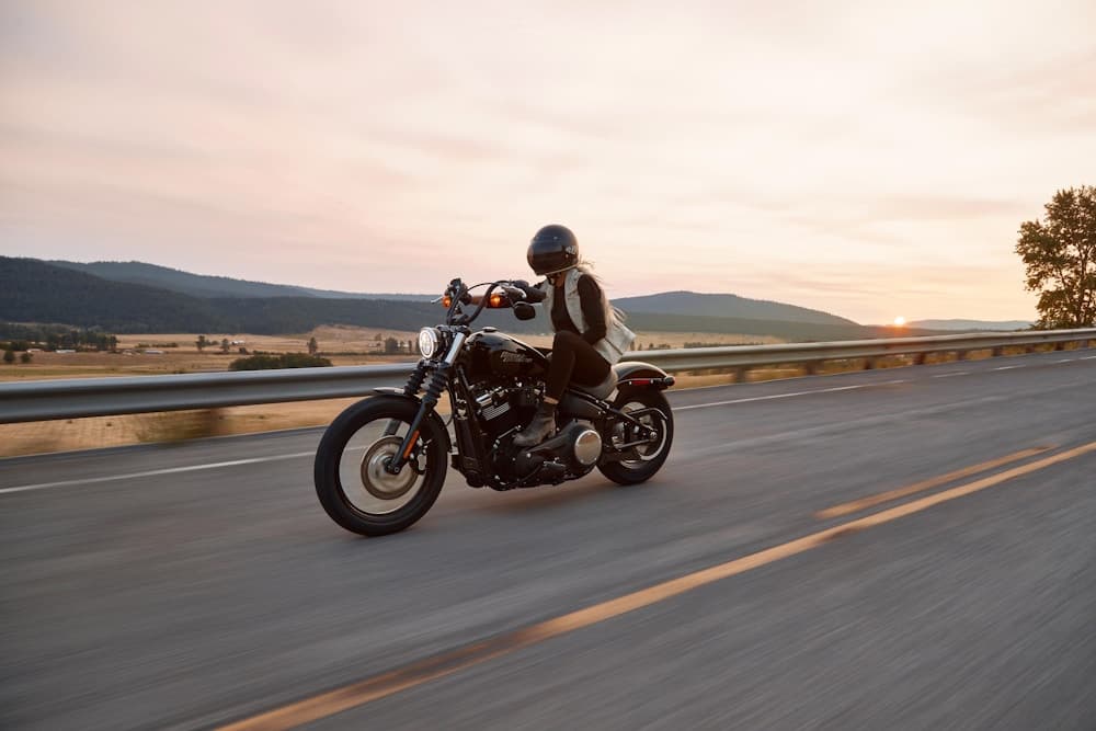 Helmeted motorcyclist riding along an open road at sunset